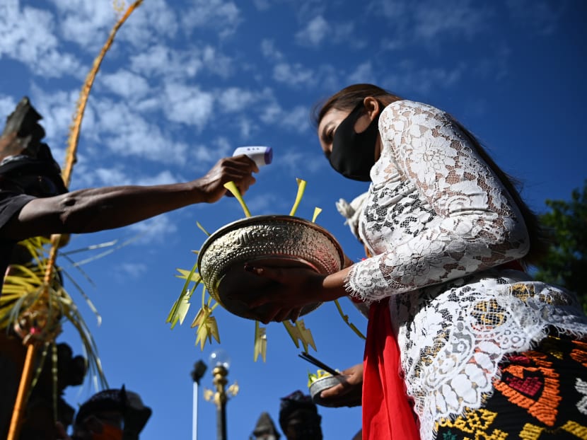 A woman has her temperature taken before a ceremony dedicated to the Hindu deity Saraswati at Jagatnatha temple in Denpasar on the Indonesian resort island of Bali on July 4, 2020. A woman has her temperature taken before a ceremony dedicated to the Hindu deity Saraswati at Jagatnatha temple in Denpasar on the Indonesian resort island of Bali on July 4, 2020.