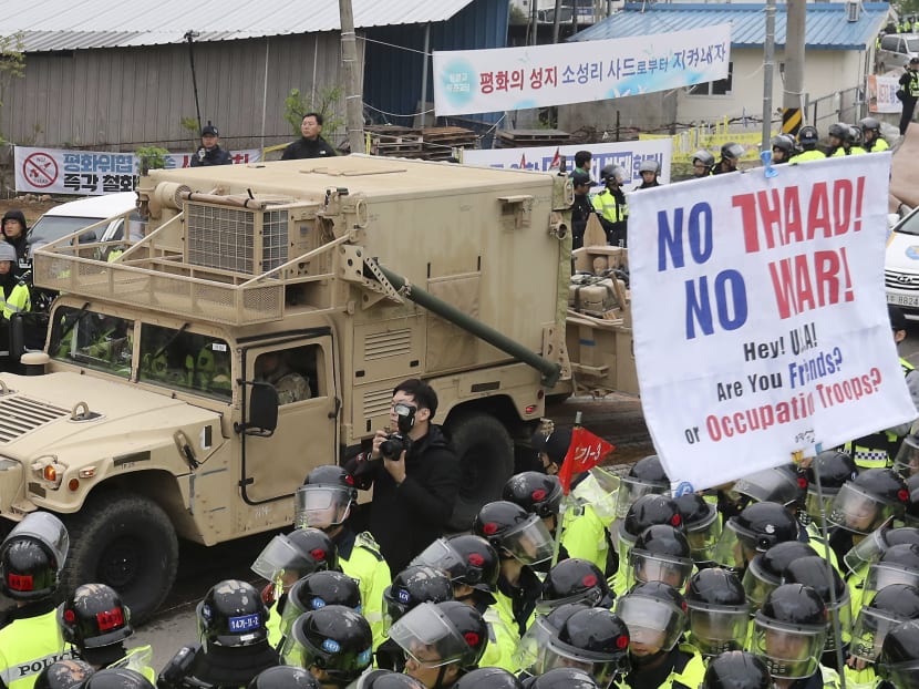 US military vehicle passes the street through banners about opposing a plan to deploy an advanced U.S. missile defense system called Terminal High-Altitude Area Defense, or THAAD, as South Korean police officers stand guard in Seongju, South Korea, April 26, 2017. Photo: Yonhap via AP