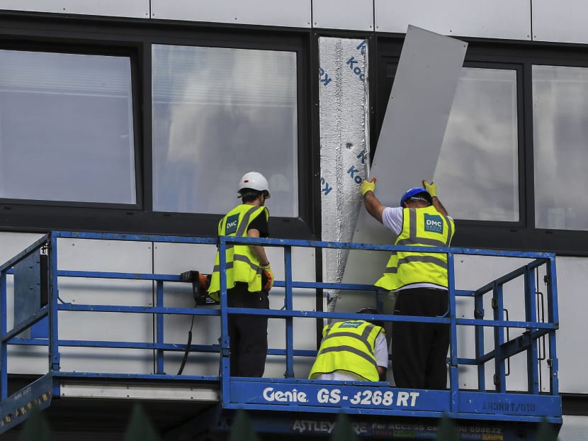 Workers remove cladding from Whitebeam Court, in Pendleton, Manchester, Monday June 26, 2017.  Photo: AP