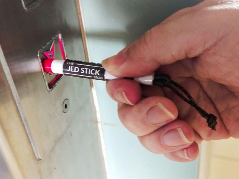 Mr Jedaiah Chen, 24, demonstrating how to use the Jed Stick 2020, a short, retractable stick made of paper to press buttons in the lift and at traffic lights.