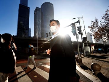 People walk across a street during morning rush hour in the central business district in Chaoyang District, Beijing, China on Nov 21, 2022.