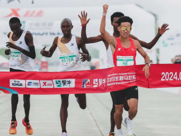 The leading runners appear to let China’s He Jie (in red) win the Beijing Half Marathon on Sunday (April 14).