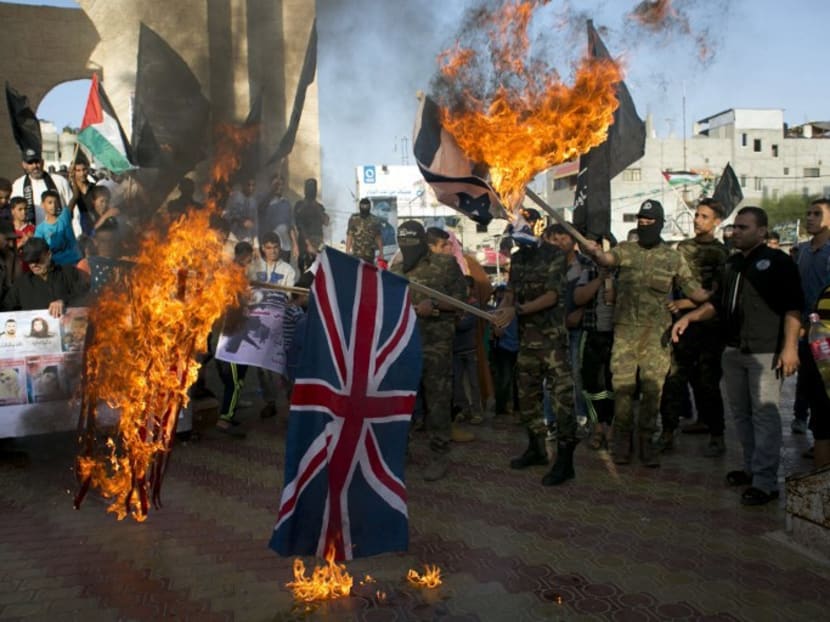 Palestinian militants of al-Nasser Salah al-Deen Brigades, the armed wing of the Popular Resistance Committees (PRC), burn the British, US and Israeli flags during a demonstration to mark the anniversary of the Balfour Declaration in the southern Gaza Strip town of Rafah on November 2, 2015. Photo: AFP