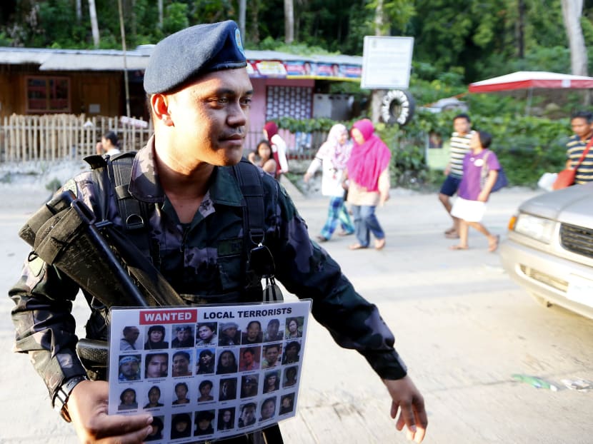 A police officer holds a poster of wanted Filipino Muslim militants known as "Maute " group at a checkpoint set up at the entrance to Iligan city Saturday, May 27, 2017 in southern Philippines. Iligan city is one of the safe havens for the tens of thousands of Marawi residents who have fled their city following the rampage by Muslim militants. Photo: AP