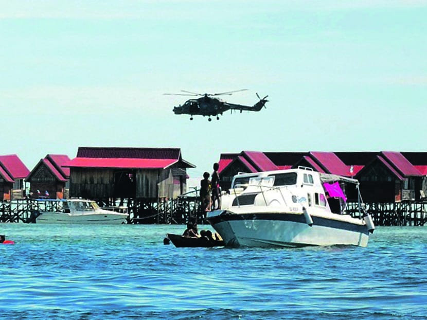A police helicopter patrolling near Mabul Water Bungalows Resort where a Malaysian policeman was killed and another is missing after they were ambushed on Saturday by a group of masked gunmen. Photo: AP
