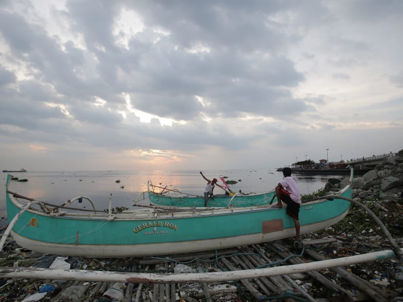 Filipino fishermen check on their boat that are docked on top of piles of garbage as they prepare for a coming storm along a coastal village in Navotas, north of Manila, Philippines on July 14, 2014. Photo: AP