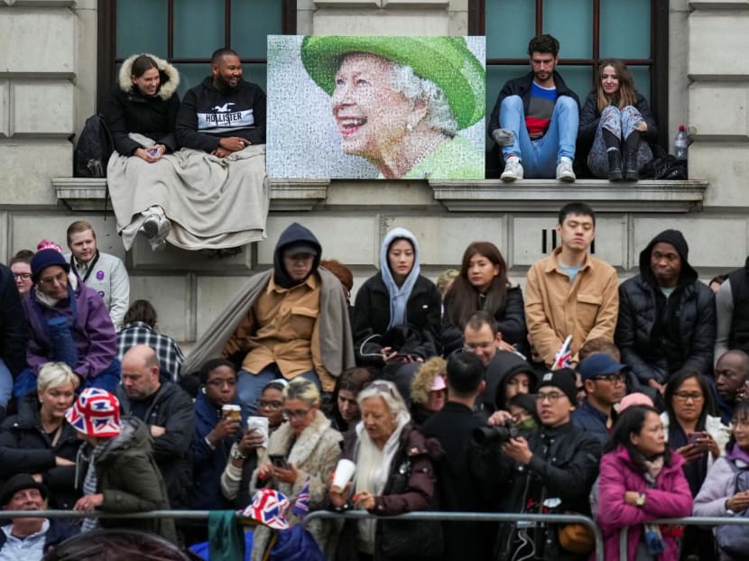 People wait along the route that the coffin of Queen Elizabeth II will be pulled on a gun carriage following her funeral service in Westminster Abbey in central London on Monday, Sept 19, 2022. 