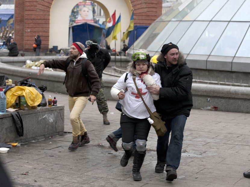 Olesya Zhukovska (left) is helped after being shot in her neck by a sniper bullet, in Independence Square, the epicenter of the country's current unrest, Kiev, Ukraine.  Photo: AP