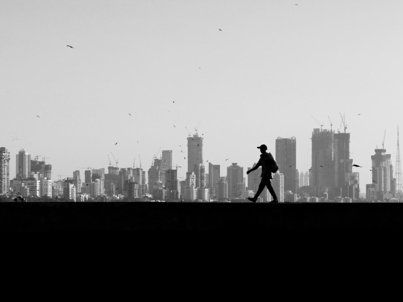 A man walks along a wall overlooking the skyline of central Mumbai’s financial district. India is regressing in global happiness rankings as a result of abysmal social capital and a lack of interpersonal trust. Photo: REUTERS