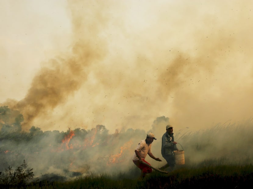 Residents carry water as they try to extinguish fires near their homes at Pal 7 village in Ogan Ilir district, Indonesia's South Sumatra province, September 3, 2015, in this photo taken by Antara Foto. Photo: Reuters