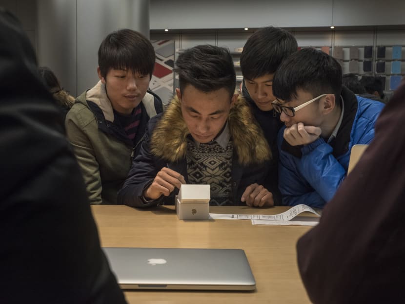 A man sets up his new iPhone 6s as friends look on at an Apple store in Beijing, Dec 19, 2015.  Photo: The New York Times