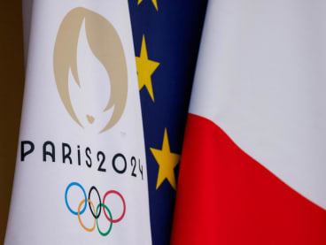 This photograph shows the Paris 2024 Olympics Games flag next to European Union and French flag at the presidential Elysee Palace in Paris, on Jan 12, 2024.