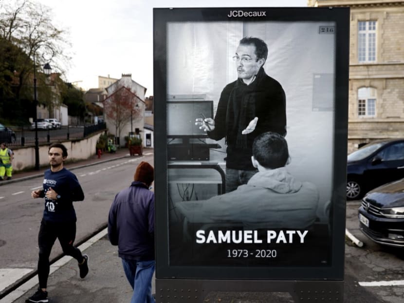 Pedestrians pass by a poster depicting French teacher Samuel Paty placed in the city centre of Conflans-Sainte-Honorine, 30km northwest of Paris, following the decapitation of the teacher on Oct 16.