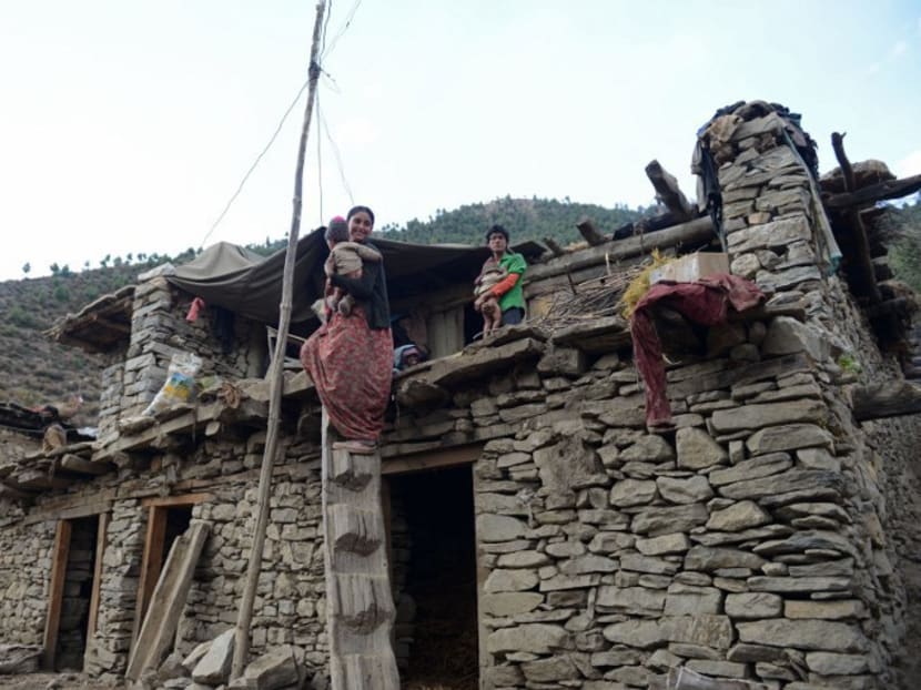 Nepalese resident Dana Sunar (left), 18, who is the last member of the Dalit caste in her class, looks on as she holds one of her children on the roof of a home in Simikot, the headquarters of Humla district, some 430 kms north-west of Kathmandu. Photo: AFP