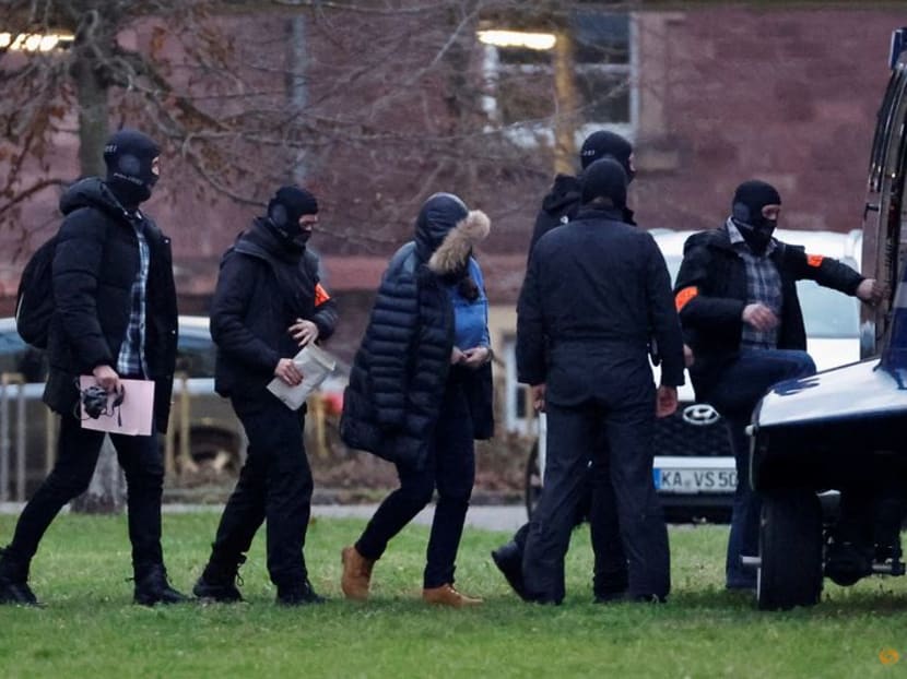 Police escorts a person after 25 suspected members and supporters of a far-right group were detained during raids across Germany, in Karlsruhe, Germany on Dec 7, 2022. 
