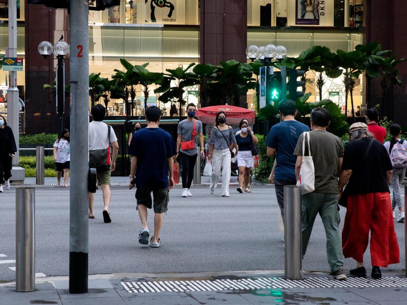 Pedestrians at a traffic crossing in front of Ngee Ann City mall along Orchard Road.
