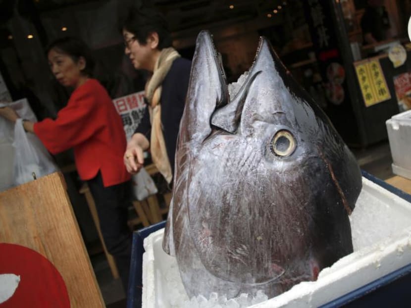 Customers walk past the head of a bluefin tuna in front of a seafood restaurant at Tsukiji fish market in Tokyo. Photo: AP