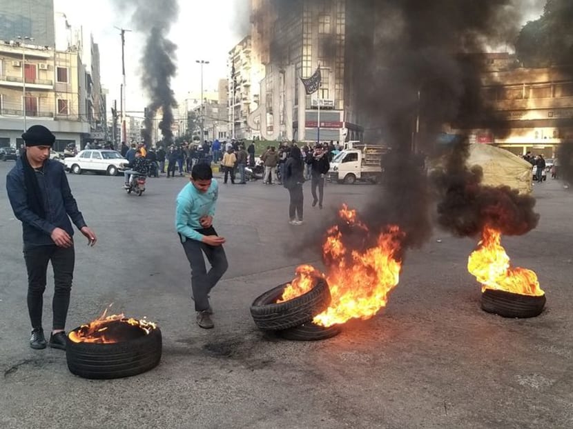 FILE PHOTO: Demonstrators stand near burning tires during a protest against the lockdown and worsening economic conditions, amid the spread of the coronavirus disease (COVID-19), in Tripoli, Lebanon January 25, 2021. REUTERS/Walid Saleh FILE PHOTO: Demonstrators stand near burning tires during a protest against the lockdown and worsening economic conditions, amid the spread of the coronavirus disease (COVID-19), in Tripoli, Lebanon January 25, 2021. REUTERS/Walid Saleh