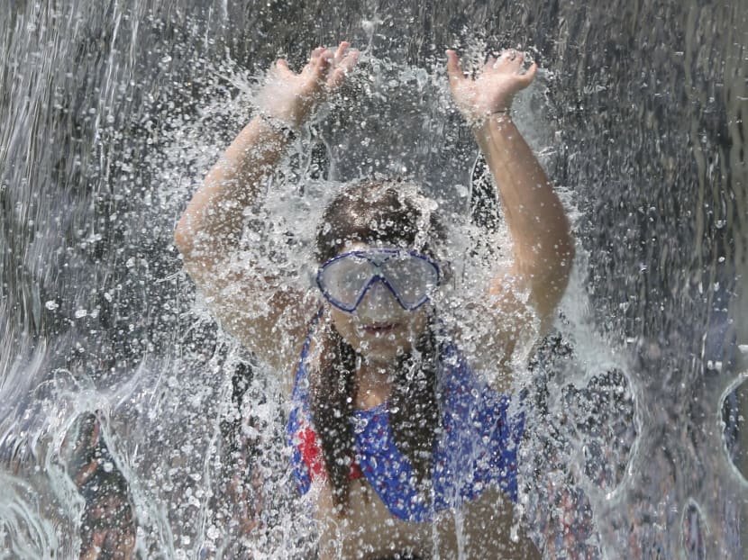 A girl plays under the waterfall at the the fun bath in Endenich, a suburb of Bonn, western Germany, July 3, 2015. Photo: Reuters