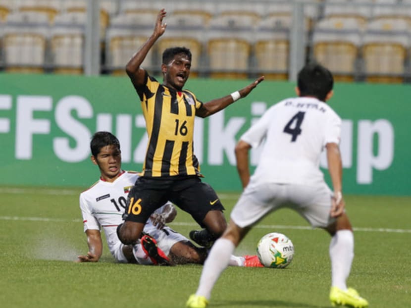 Malaysia's Subramaniam Kunanlan (centre) reacts as he is tackled by Myanmar's Kyaw Ko Ko (left) as Myanmar's David Htan runs into support during their AFF Suzuki Cup Group B soccer match on Nov 23, 2014. Photo: AP