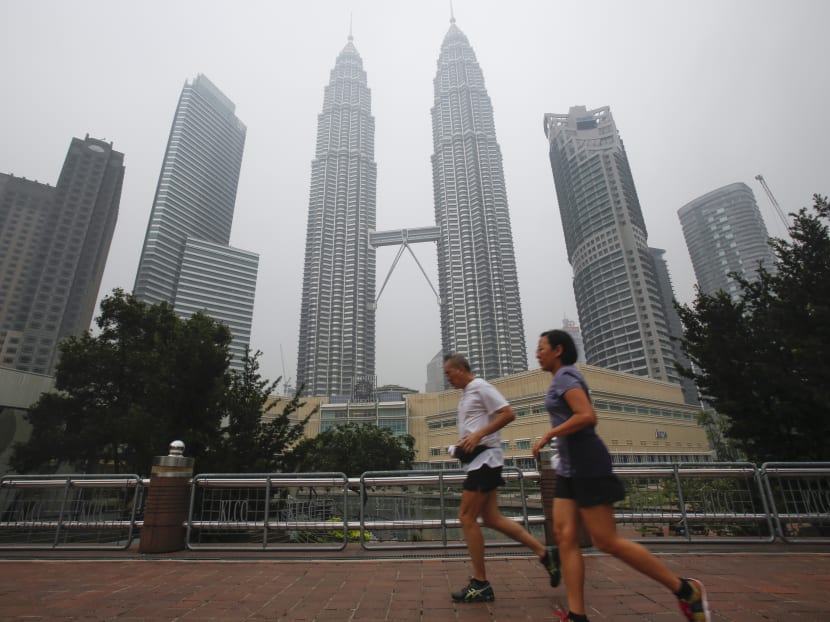 Malaysians jog past Malaysia's landmark building, Petronas Twin Towers shrouded with haze in Kuala Lumpur, Malaysia on Sept 28, 2015. Photo: AP