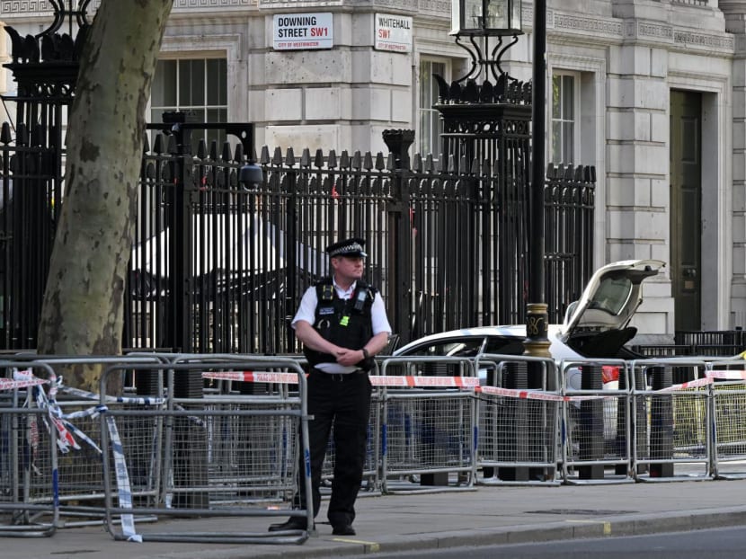 A police officer stands guard near to a car, seen at the gates of Downing Street in central London after it crashed into its front gates on May 25, 2023.