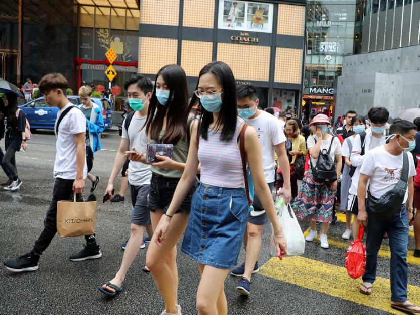Tourists wearing masks cross a street outside a shopping mall in Kuala Lumpur.