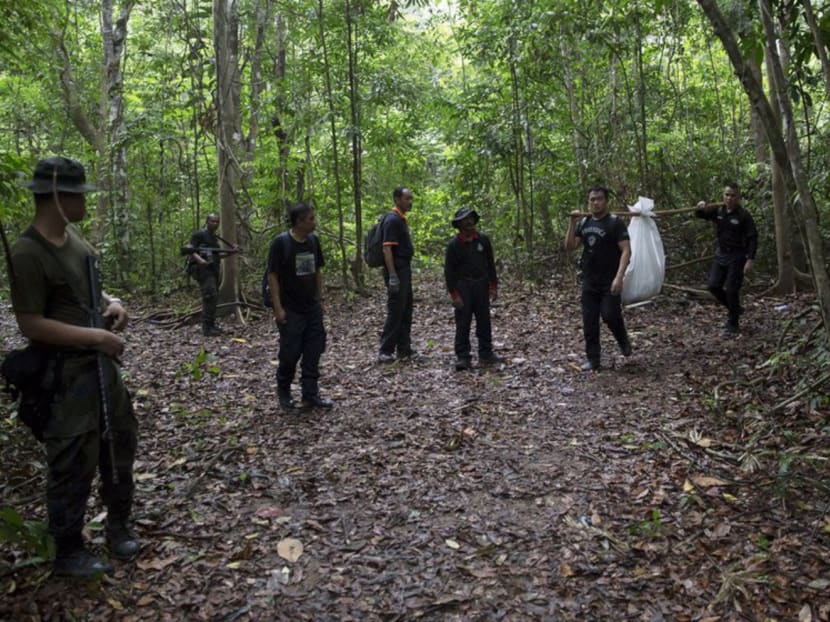 A police forensic team carrying a body bag with human remains that were dug up near an abandoned human-trafficking camp at Bukit Wang Burma, close to the Thai border, in northern Malaysia on Wednesday. Photo: Reuters