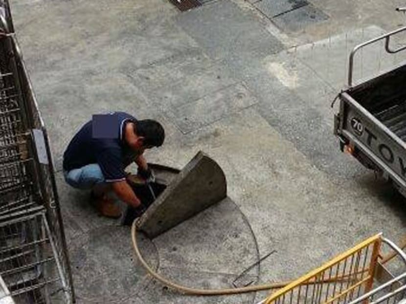 A man extracting used cooking oil from a sewer. Photo: Channel 8 News viewer Mr Tan