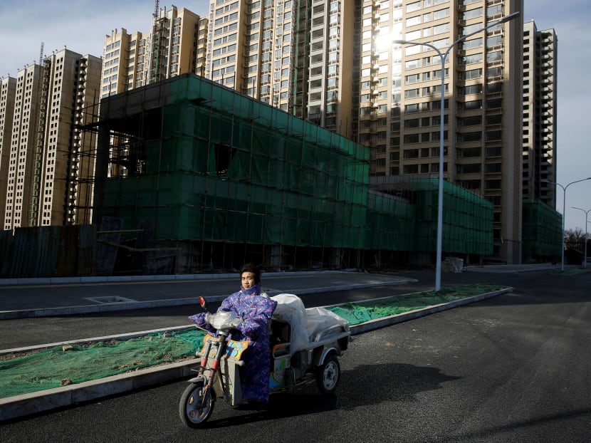 A man rides an electric tricycle past residential apartment blocks under construction on the outskirts of Beijing. China is considering adopting a property tax that could dramatically reshape the world’s second-largest economy. Photo: Reuters