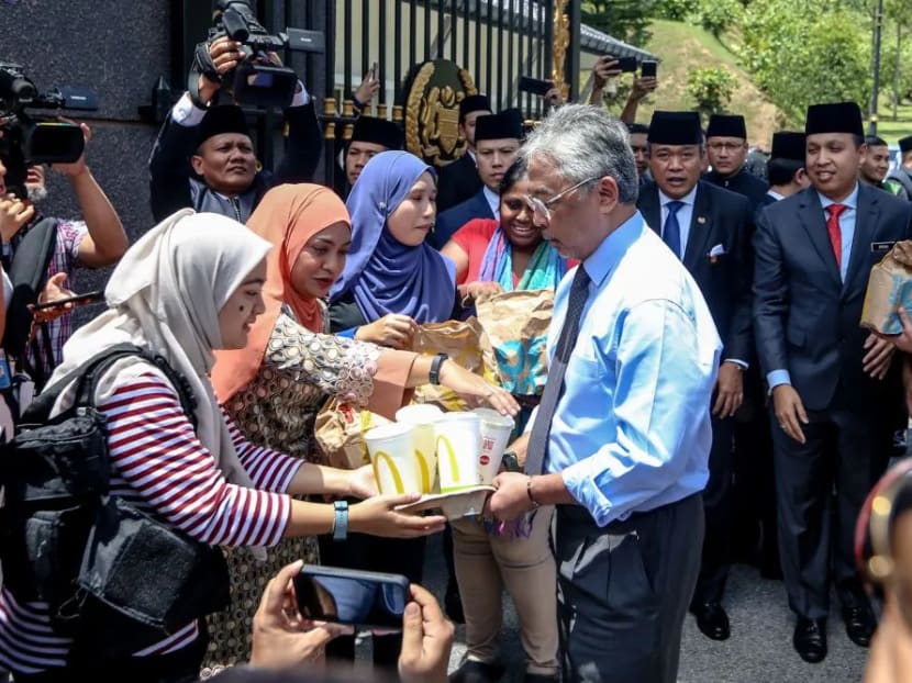 The King of Malaysia (centre) distributes food from McDonald's to members of the media at Istana Negara, Feb 25, 2020.