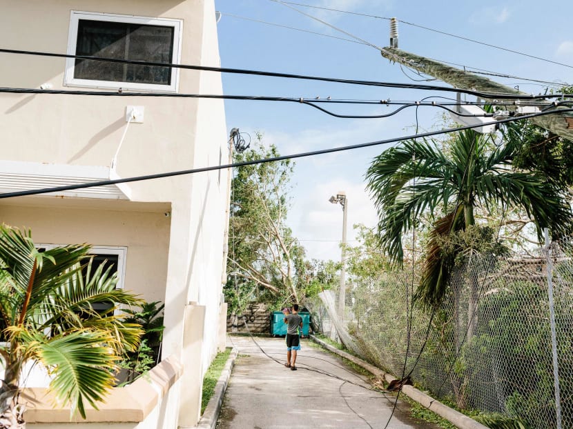 A boy carries a child over wires from a downed utility pole in the Wynwood neighborhood of Miami, Sept. 11, 2017. About 70 percent of the city remained without electricity Monday in the wake of Hurricane Irma, and roads were not only impassable but traffic lights were not working, city officials said. Photo: The New York Times