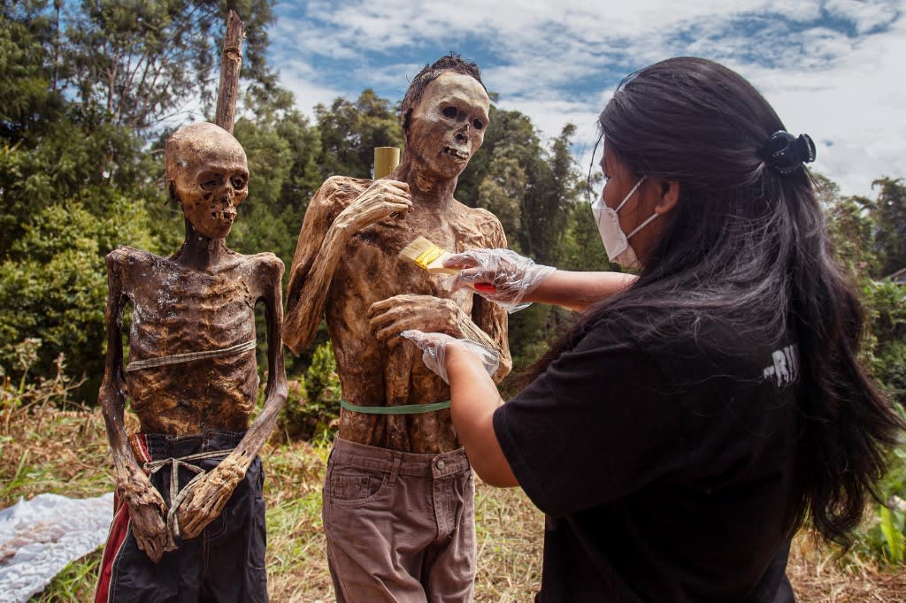 This picture taken on Aug 17, 2022 shows a family member of the Toraja ethnic group preparing the bodies of exhumed relatives from a community burial site to be cleaned and dressed in a series of traditional ceremonies honouring the dead known as "Manene", in Torea village, in North Toraja, Indonesia's South Sulawesi. This picture taken on Aug 17, 2022 shows a family member of the Toraja ethnic group preparing the bodies of exhumed relatives from a community burial site to be cleaned and dressed in a series of traditional ceremonies honouring the dead known as "Manene", in Torea village, in North Toraja, Indonesia's South Sulawesi.