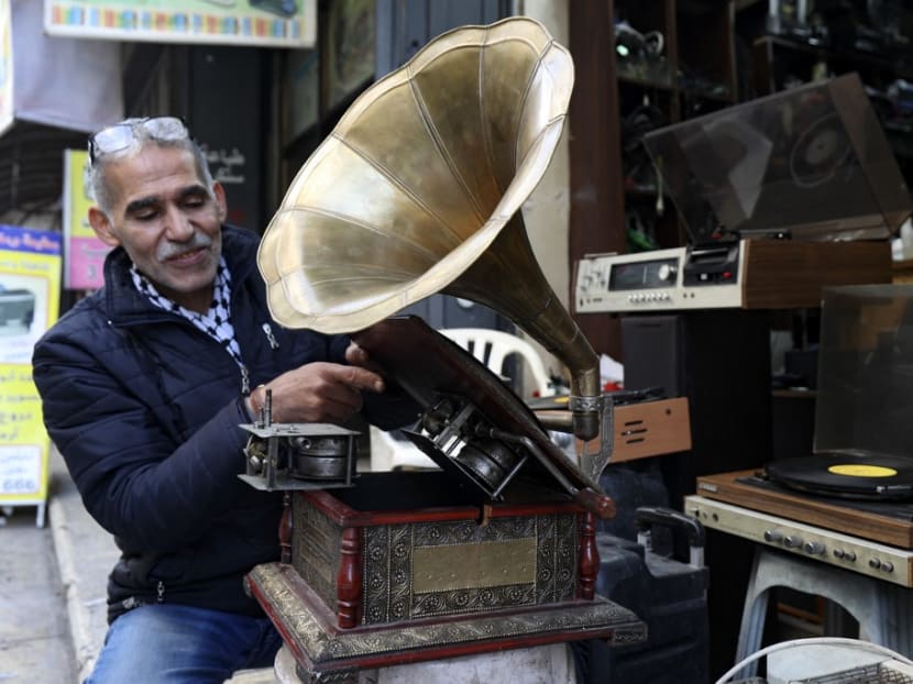 Palestinian Jamal Hemmou checks an antique gramophone (phonograph) record player in front of his shop in the occupied-West Bank city of Nablus, on Jan 17, 2023. 