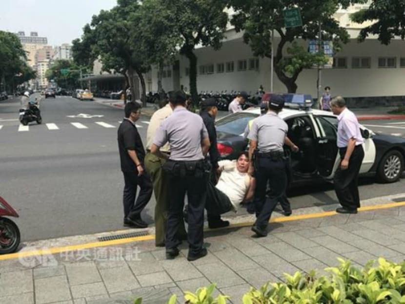 The assailant, seen here being taken away by police officers, had slashed a military police guard outside Taiwan's presidential office. Photo: Focus Taiwan's Twitter page