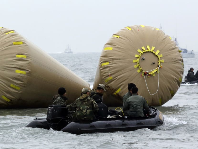 South Korean Navy soldiers try to rescue passengers trapped in the sunken 6,852-ton ferry Sewol near the buoys which were installed to mark the vessel in the water off the southern coast near Jindo, south of Seoul, South Korea, Saturday, April 19, 2014. Photo: AP
