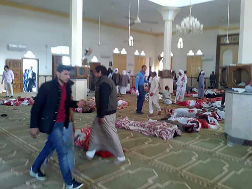 Egyptians walk past bodies following a gun and bombing attack at the Rawda mosque. A bomb explosion ripped through the mosque before gunmen opened fire on the worshippers. Photo: AFP