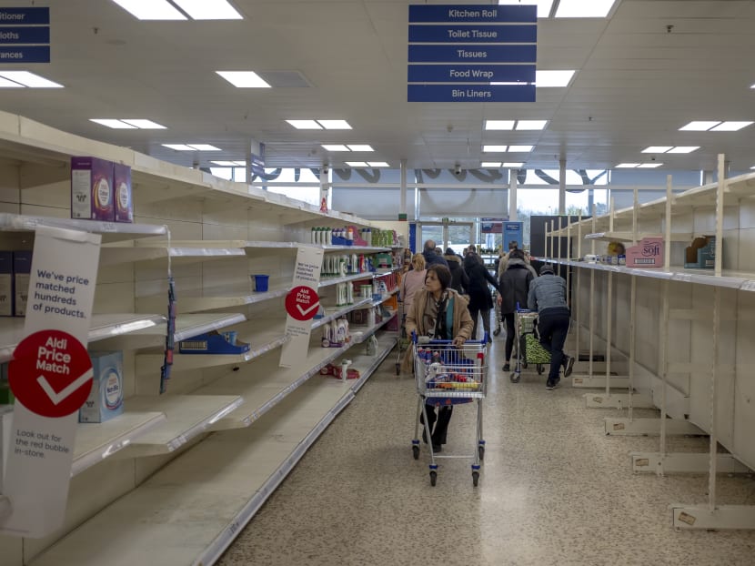 An aisle bare of toilet paper and paper towels at a supermarket in London, March 15, 2020. The author notes that panic-buying illustrates an underlying logic of self-preservation amid uncertainty – and a lack of trust in the system to prevail.