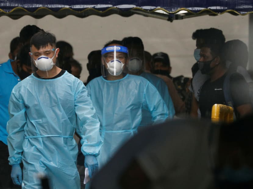 Personnel in protective garment usher a group of migrant workers to take a bus to a government quarantine facility after workers were tested positive for Covid-19 at Westlite Woodlands dormitory in Singapore on April 22, 2021. Personnel in protective garment usher a group of migrant workers to take a bus to a government quarantine facility after workers were tested positive for Covid-19 at Westlite Woodlands dormitory in Singapore on April 22, 2021.