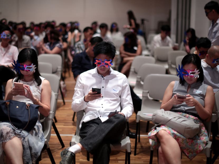 Participants of a mass speed dating event in February 2016 using their mobile phones and wearing masks to help self-conscious singles step out of their comfort zone.