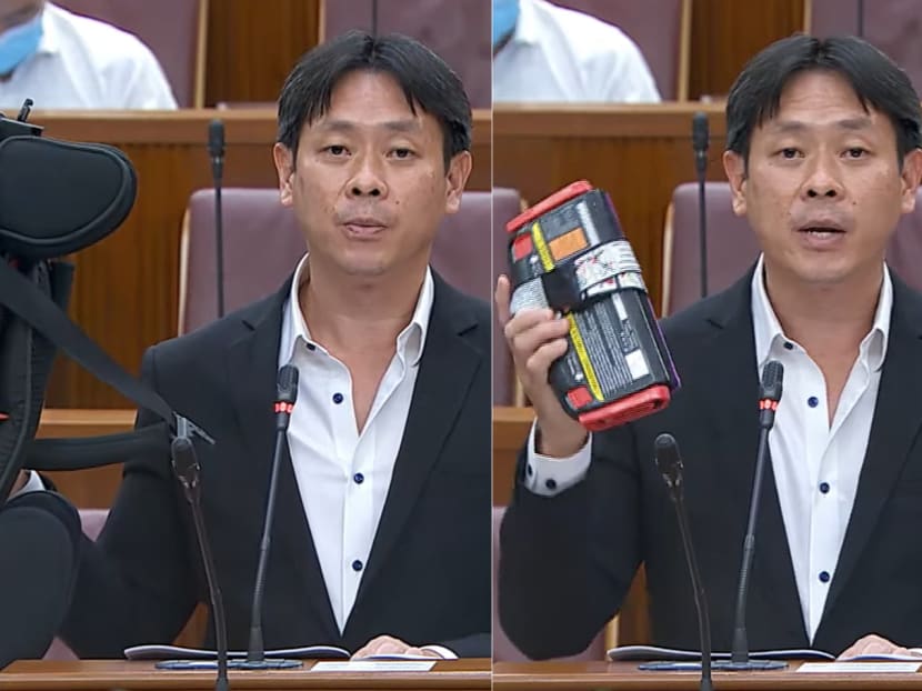 Member of Parliament Louis Ng holding up samples of child booster seats during his speech on May 12, 2021.