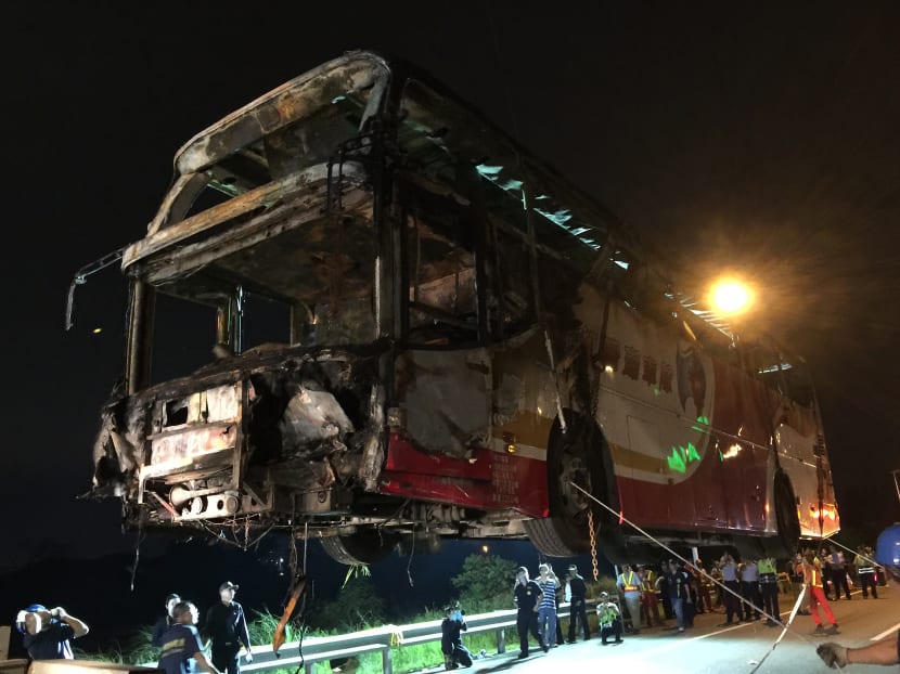 Taiwan police taking photos of the bottom of a bus as it is hoisted up by a crane after it earlier crashed and caught fire along an expressway on its way to the airport in Taiwan's city of Taoyuan. Photo: Central News Agency via AFP