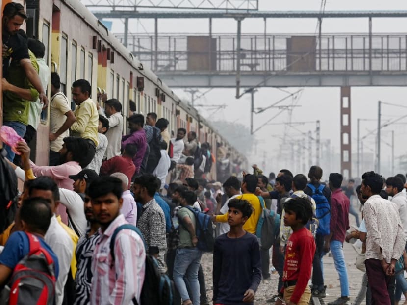 Commuters board an overcrowded train near a railway station at Loni town in India's state of Uttar Pradesh on April 24, 2023.