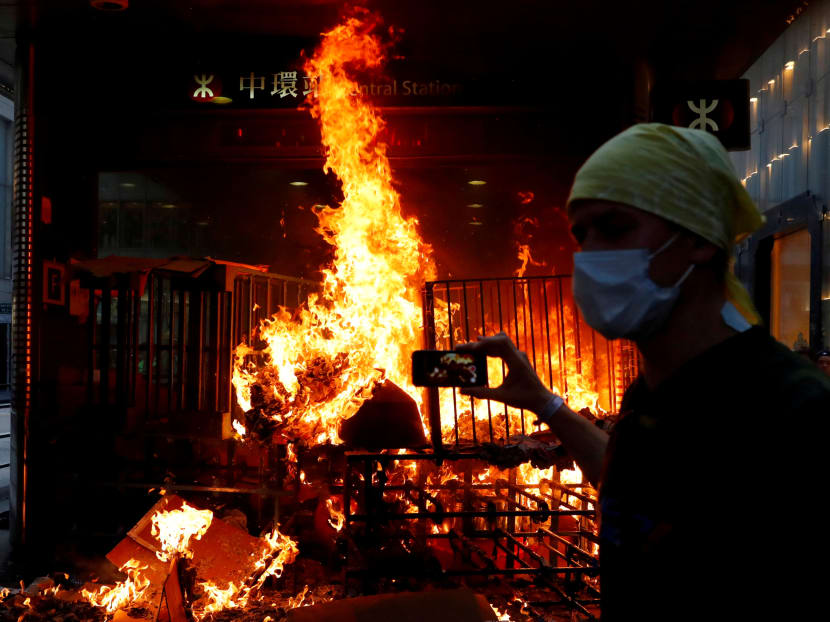A protester films a fire at the entrance of MTR Central Station in Hong Kong on Sept 8, 2019. A protester films a fire at the entrance of MTR Central Station in Hong Kong on Sept 8, 2019.