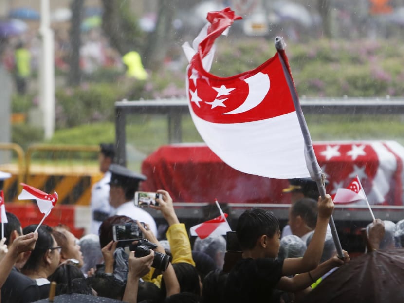 A boy waves the national flag as the funeral procession of the late Mr Lee Kuan Yew leaves Parliament House on March 29, 2015. Photo: Raj Nadarajan