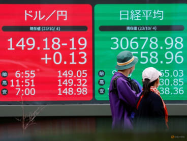 A man looks at an electric monitor displaying the Japanese yen exchange rate against the U.S. dollar and Nikkei share average outside a brokerage in Tokyo, Japan October 4, 2023. REUTERS/Issei Kato