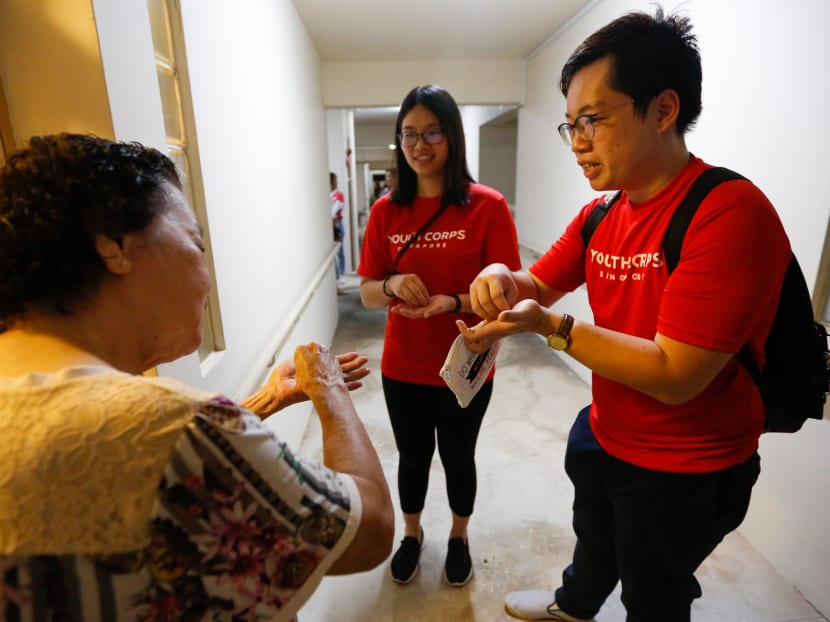 Madam Oh Siew Hong (left), 83, gets some tips on hygiene and hand washing from youth volunteers Vincent Thian Chuan Keng (right), 23, and Ramona Wong, 26.