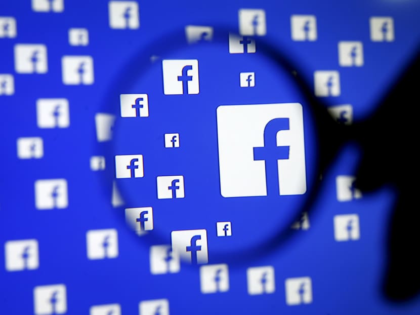 A man poses with a magnifier in front of a Facebook logo on display in this illustration taken Dec 16, 2015. Photo: Reuters