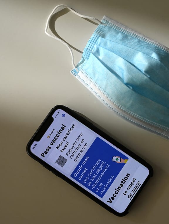 A face mask and a health pass on a mobile phone screen connected to a Covid-19 tracing application in France, which allows people vaccinated against Covid-19 to access bars, restaurants or regional transports.