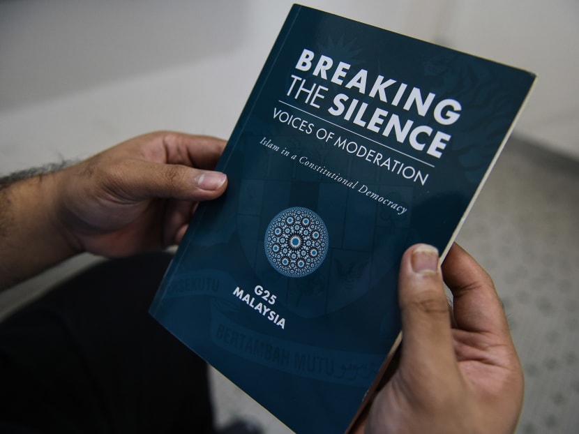 In this photo illustration taken in Kuala Lumpur on August 1, 2017, a man holds the book "Breaking The Silence: Voices Of Moderation - Islam In A Constitutional Democracy". Photo: AFP